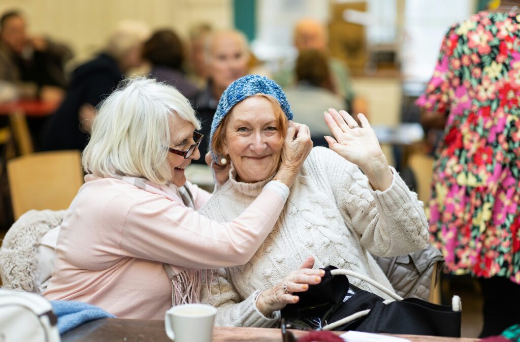 A woman puts crochet on another woman's head